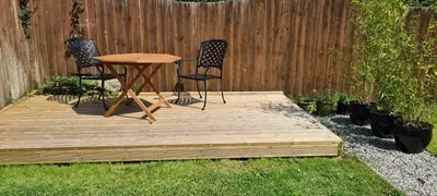 a wooden deck with two chairs and a table in a yard at Rockley Cottage, close to Eden project and Fowey. in Bodmin
