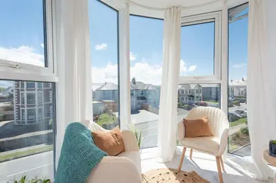 a living room with two chairs and large windows at 45 Ocean 1, Newquay in Crantock