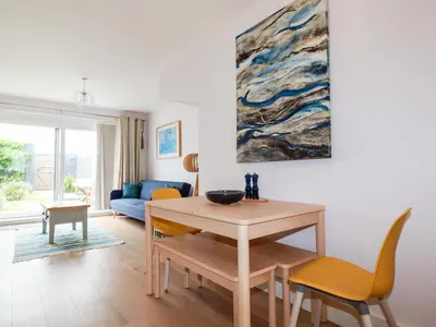 a living room with a table and chairs and a painting at 6 Ocean Heights in Newquay