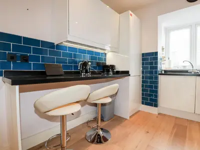 a kitchen with two stools and a counter with blue tiles at 6 Ocean Heights in Newquay