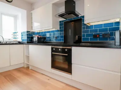a kitchen with white cabinets and a black oven at 6 Ocean Heights in Newquay