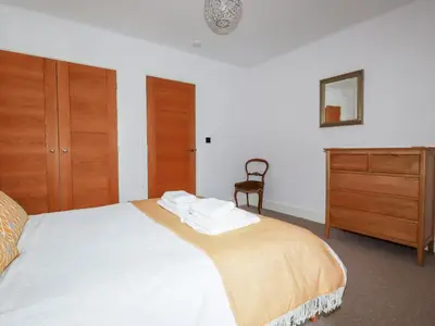a bedroom with a bed with white sheets and a dresser at 6 Ocean Heights in Newquay
