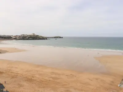 a beach with people walking in the water at 6 Ocean Heights in Newquay