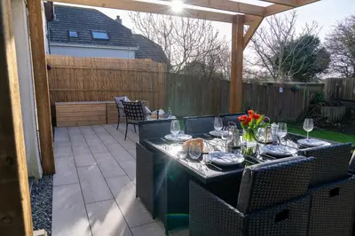 a patio with a table and chairs with wine glasses at Trelowen in Padstow