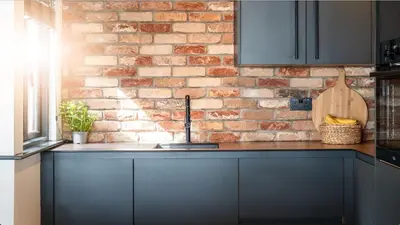 a kitchen with a brick wall and a sink at Stunning Waterfront Apartment With Spectacular Views & Parking at 'CAPTAINS LOFT' in Falmouth