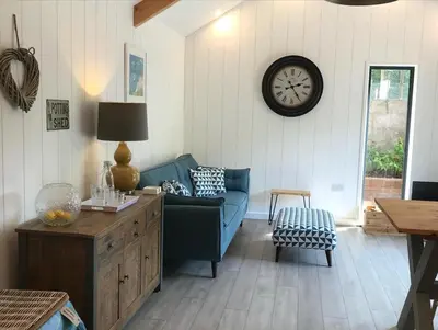 a living room with a couch and a clock on the wall at The Potting Shed in St Austell