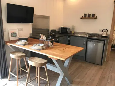a kitchen with a wooden table and two stools at The Potting Shed in St Austell