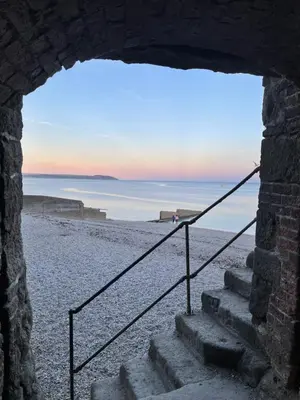 a view of the beach through a stone window at The Potting Shed in St Austell