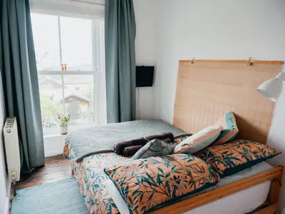 a bed in a bedroom with a large window at Enchanted Rose Garden House in Falmouth