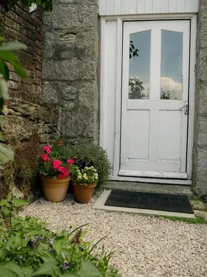 two pots of flowers sitting in front of a door at Enchanted Rose Garden House in Falmouth