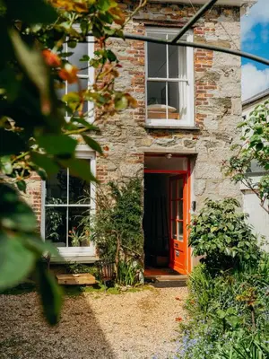 a brick house with an orange door at Enchanted Rose Garden House in Falmouth