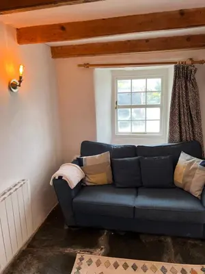 a blue couch in a room with a window at The Cottage St Kew in Port Isaac