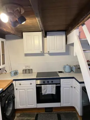 a kitchen with white cabinets and a stove top oven at The Cottage St Kew in Port Isaac