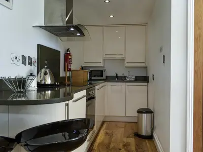a kitchen with white cabinets and a black counter top at Trenpeskador - Uk39442 in Saint Columb Minor