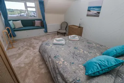 a bedroom with a bed with blue pillows and a couch at Flat 6 in Falmouth