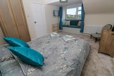 a bedroom with a bed with blue pillows and a couch at Flat 6 in Falmouth