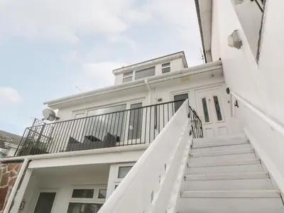 a white house with stairs leading up to the front door at Flat 6 in Falmouth