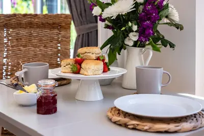 a table with two plates of food and a vase with flowers at Chi Lowarth in Helston