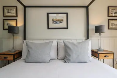 a bedroom with a white bed with pillows and two lamps at Chi Lowarth in Helston