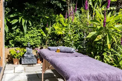 a bed with a purple blanket in a garden at Chi Lowarth in Helston
