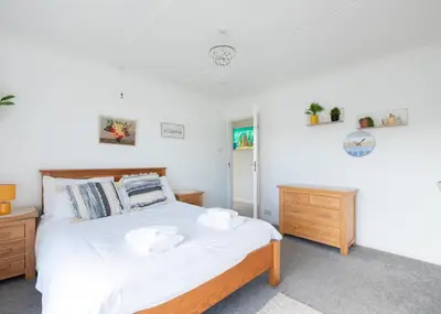 a bedroom with a bed with white sheets and wooden furniture at Beach Haven in Wadebridge