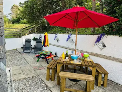 a picnic table with a red umbrella on a patio at Baywatch Sands in Wadebridge