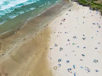 a group of people on a beach near the ocean at Baywatch Sands in Wadebridge