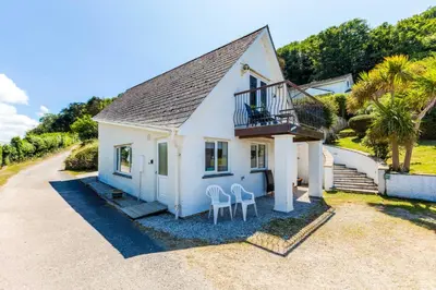 a white house with two chairs on a gravel driveway at Baywatch Sands in Wadebridge