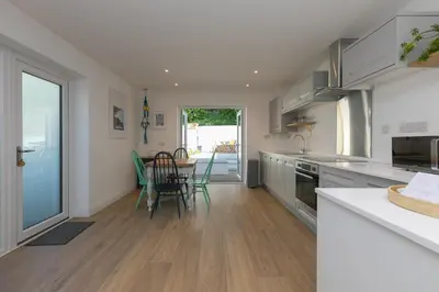 a kitchen with white cabinets and a table with chairs at Hillywych Studio in Redruth