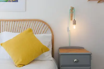 a yellow pillow sitting on a bed next to a nightstand at Hillywych Studio in Redruth