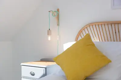 a yellow pillow sitting on a bed next to a nightstand at Hillywych Studio in Redruth