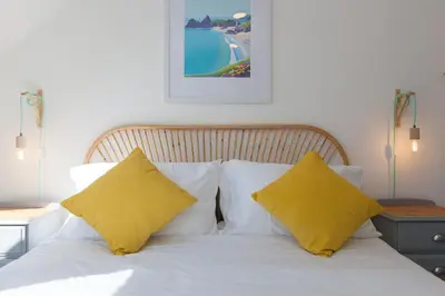 a bed with two yellow pillows on top of it at Hillywych Studio in Redruth