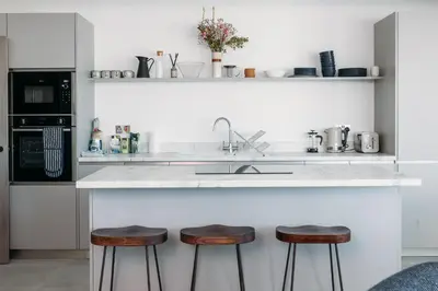 a kitchen with a counter with stools and a sink at Luxury Family Apartment with sea views in Newquay