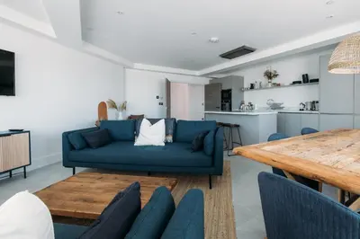a living room with a blue couch and a table at Luxury Family Apartment with sea views in Newquay