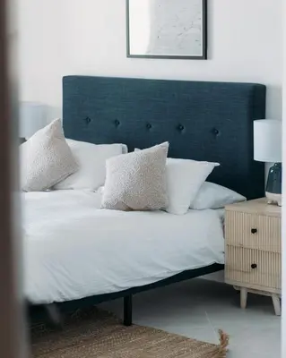 a bed with white pillows and a blue headboard at Luxury Family Apartment with sea views in Newquay
