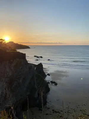 a sunset over a beach with the ocean and rocks at Luxury Family Apartment with sea views in Newquay