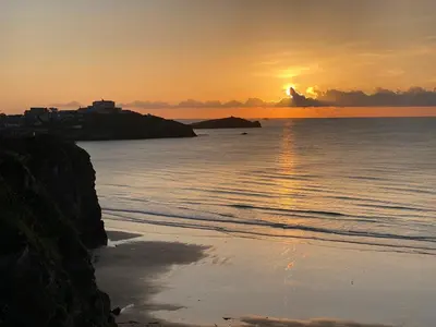 a sunset over the ocean with a beach at Luxury Family Apartment with sea views in Newquay