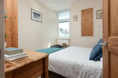 a bedroom with a bed and a desk with books at Cormorant Views, Marazion in Marazion
