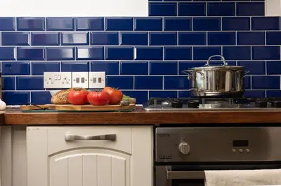 a blue tiled kitchen with apples on a cutting board at Cormorant Views, Marazion in Marazion