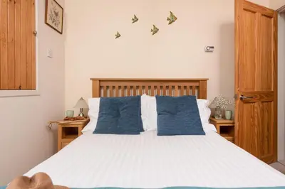 a bedroom with a large bed with blue pillows at Cormorant Views, Marazion in Marazion