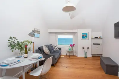 a living room with a couch and a table at Stunning Sea Views, Wi-Fi, Pet Friendly in Marazion