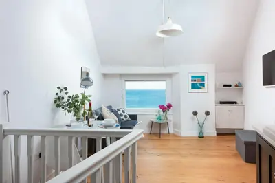 a white living room with a table and a couch at Stunning Sea Views, Wi-Fi, Pet Friendly in Marazion