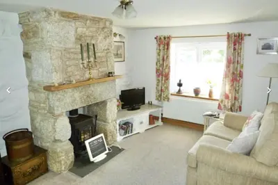 a living room with a stone fireplace and a couch at Lovely Cornish cottage in small village setting in Saint Hilary