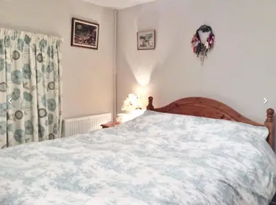 a bedroom with a bed with a white comforter at Lovely Cornish cottage in small village setting in Saint Hilary