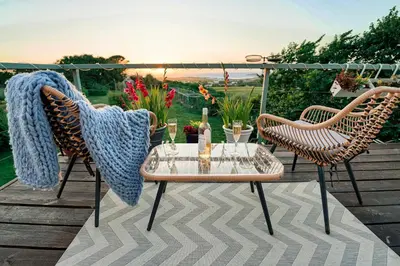 a patio with two chairs and a table on a deck at Spacious Sea-View Apt. Overlooking St Ives Bay in Gwithian