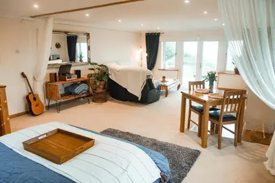a bedroom with a bed and a desk with a guitar at Spacious Sea-View Apt. Overlooking St Ives Bay in Gwithian