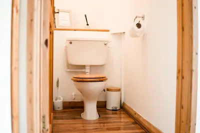 a toilet in a small bathroom with a wooden floor at Spacious Sea-View Apt. Overlooking St Ives Bay in Gwithian