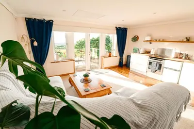 a living room with a couch and a table at Spacious Sea-View Apt. Overlooking St Ives Bay in Gwithian