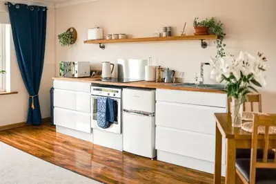 a kitchen with white cabinets and a wooden floor at Spacious Sea-View Apt. Overlooking St Ives Bay in Gwithian