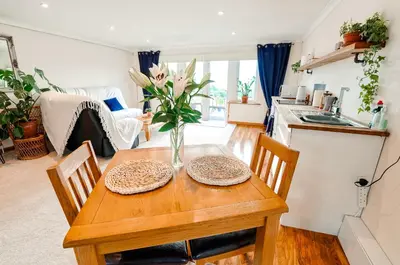 a dining room table with a vase of flowers on it at Spacious Sea-View Apt. Overlooking St Ives Bay in Gwithian